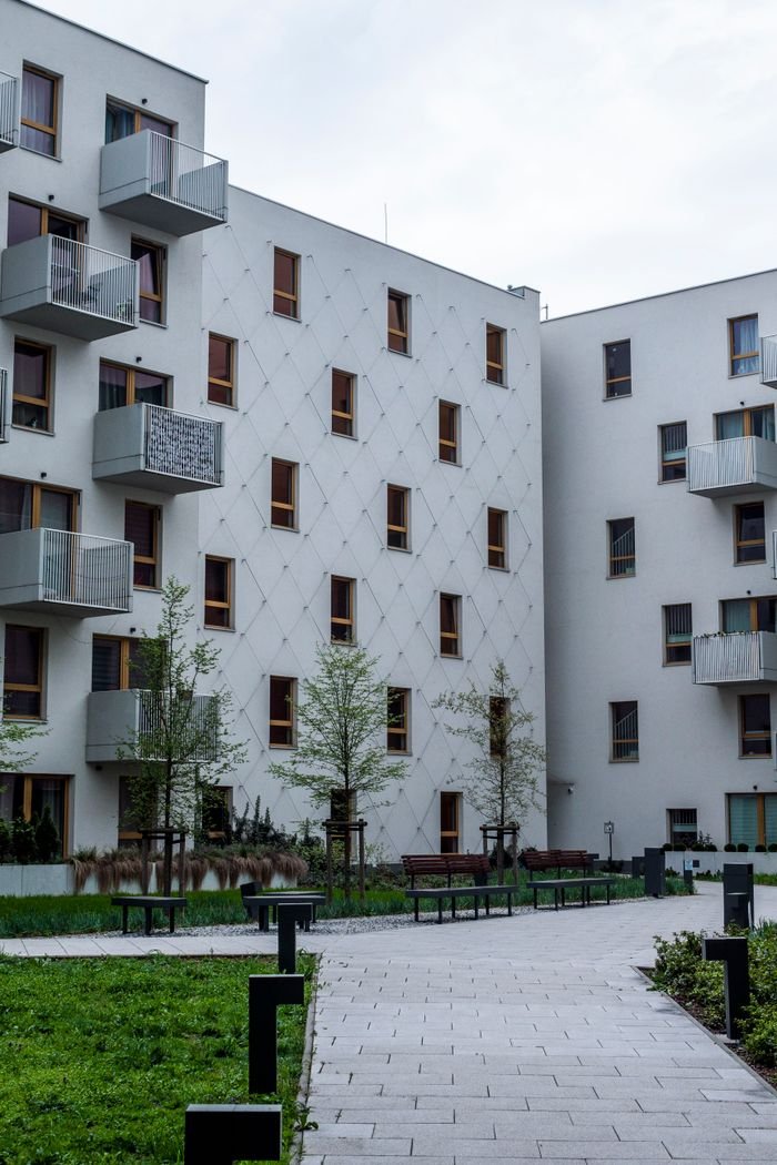 services-03 Contemporary white urban apartment buildings with balconies and greenery.