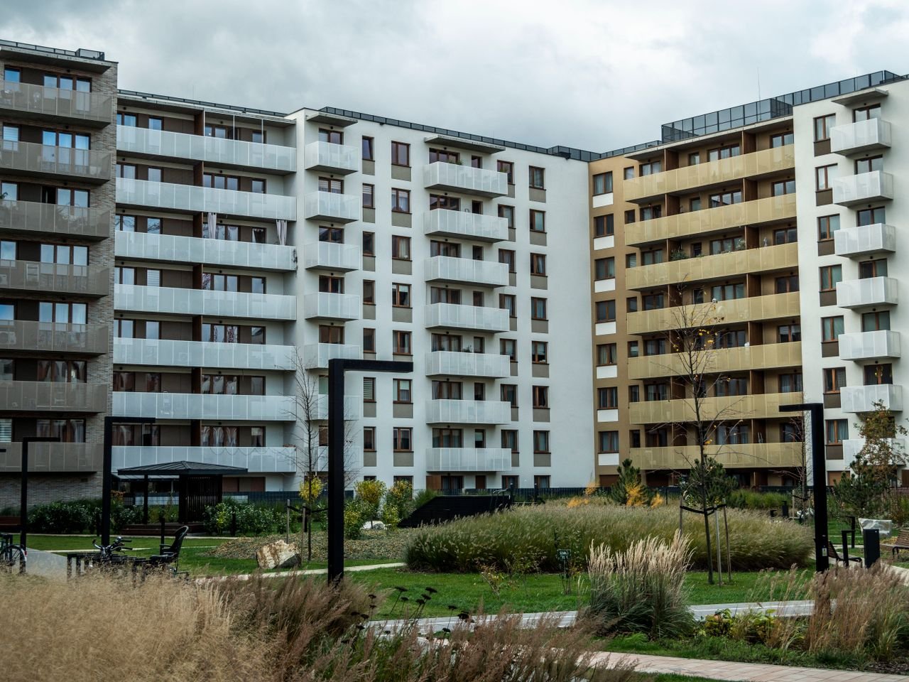 Mastering the First Impression: Your intriguing post title goes here A modern apartment building surrounded by landscaped greenery under a cloudy sky.
